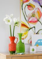 Vases en verre colorés sur buffet avec peinture florale