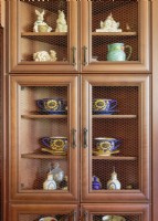 Les trésors exposés dans une armoire à façade grillagée comprennent des tasses et soucoupes à tournesol vintage, des pots à moutarde,